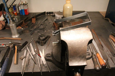 The Zundapp KS601 battery strap in the vise on the workbench.